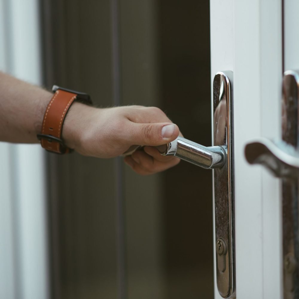 A closeup shot of a person holding a door knob and opening the door